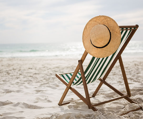 Liegestuhl mit Strohhut am Strand